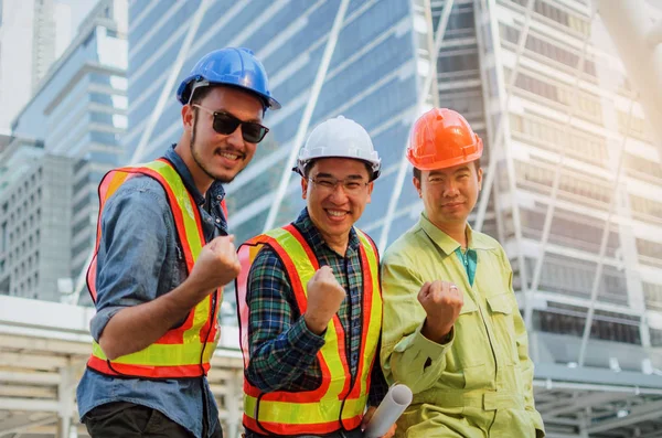 最後に私たちがやった エンジニア 技術者および建物の背景には 近代的な都市で一緒に立っているその強力な手を示す悲鳴している建築家のグループ建設サイトと業界の概念 — ストック写真