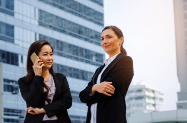 cep telefonu ve silah ile iki iş Asya ve beyaz kadın ayakta modern şehir, başarılı, destek, Toplantı, ortağı, ekip çalışması, güven, Internet, ağ bağlantı kavramı içinde geçti
