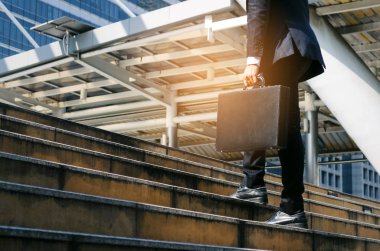 Büyüyünce evrak çantası ve sabah zaman işe yarayacak şehir, kararlılık, güven, yaşam tarzı, Bitirim, merdivenlerden yukarı yürümek tutan genç yakışıklı iş adamı ve başarılı konsept