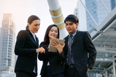 Grup iş adamları konuşuyor ve finans haberleri içinde hareket eden hakkında bilgi okuma elbiseli tablet birlikte ayakta modern şehir, ağ teknolojisi, Internet, başarılı, ekip çalışması kavramı