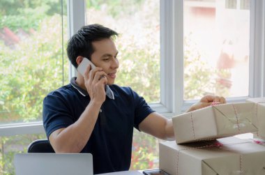 Başlamak yukarıya. genç adam yeni dizüstü bilgisayar, cep telefonu, teslim ambalaj kutusu tablo, evde çalışma office, KOBİ, küçük işletme sahibi ile müşteri online kavramı alışveriş siparişinden sonra mutlu