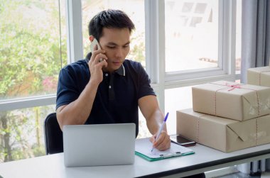 Başlamak yukarıya. genç adam yeni klibi kurulu, cep telefonu ve teslim ambalaj kutusu tablo, evde çalışma office, KOBİ, küçük işletme sahibi ile müşteri online kavramı alışveriş siparişinden sonra mutlu