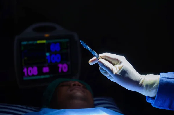 医生的手拿着手术刀刀外科医生工作 而病人在床上心电图 心电图监测显示心率在手术室医院 急诊室 医疗保健概念 — 图库照片