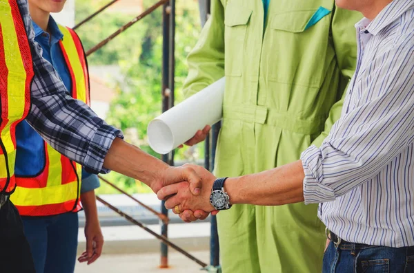 Deal, close up shaking hands of contractor, engineer and technician after finishing up business meeting to greeting start up project contract in construction site, partnership and teamwork concept