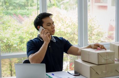 Başlamak yukarıya. genç adam yeni dizüstü bilgisayar, cep telefonu, teslim ambalaj kutusu tablo, evde çalışma office, KOBİ, küçük işletme sahibi ile müşteri online kavramı alışveriş siparişinden sonra mutlu