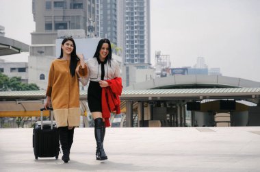 Bagaj birlikte kış sezonunda büyük şehirde seyahat ile. iki güzel neşeli Asya ve beyaz genç kadın arkadaş seyahat, alışveriş, yaşam tarzı, moda, dostluk ve tatil kavramı