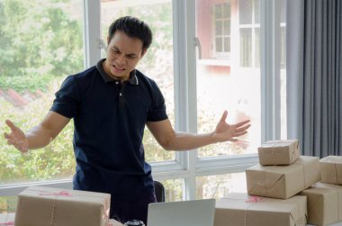 Başlamak yukarıya. Depresif, hayal kırıklığına, vurguladı. Online kavramı alışveriş dizüstü bilgisayar ve teslim ambalaj kutusu masada, evde çalışma office, KOBİ, küçük işletme sahibi çalışma genç Asyalı adam