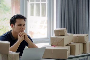 Başlamak yukarıya. Depresif, hayal kırıklığına, vurguladı. Online kavramı alışveriş dizüstü bilgisayar ve teslim ambalaj kutusu masada, evde çalışma office, KOBİ, küçük işletme sahibi çalışma genç Asyalı adam