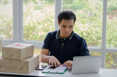 Başlamak yukarıya. genç adam yeni dizüstü bilgisayar, cep telefonu, teslim ambalaj kutusu tablo, evde çalışma office, KOBİ, küçük işletme sahibi ile müşteri online kavramı alışveriş siparişinden sonra mutlu