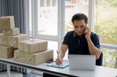 Başlamak yukarıya. genç adam yeni dizüstü bilgisayar, cep telefonu, teslim ambalaj kutusu tablo, evde çalışma office, KOBİ, küçük işletme sahibi ile müşteri online kavramı alışveriş siparişinden sonra mutlu