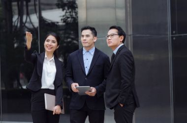 Grup içinde iş insan konuşmaya uygun ve dizüstü bilgisayar birlikte ayakta modern şehir, finans haberleri hakkında bilgi okuma teknolojisi, Internet, başarılı, ekip çalışması kavramı ağ