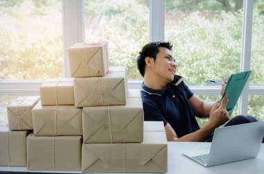 Başlamak yukarıya. genç adam yeni klibi kurulu, cep telefonu ve teslimat parsel kutusu tablo, evde çalışma office, KOBİ, küçük işletme sahibi ile müşteri online kavramı alışveriş siparişinden sonra mutlu