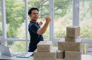 Başlamak yukarıya. genç adam yeni dizüstü bilgisayar, cep telefonu, teslim ambalaj kutusu tablo, evde çalışma office, KOBİ, küçük işletme sahibi ile müşteri online kavramı alışveriş siparişinden sonra mutlu