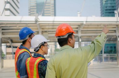 Yan Görünüm grubunda mühendis, teknisyen ve mimar ile modern şehir bina arka plan, şantiye, sanayi ve işçi kavramı planı plan bina hakkında planlama güvenlik kask