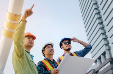 group of engineer, technician and architect planning about new project building plan with blueprint in modern city building background, contractor, construction site, business and industry concept