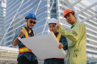 grup mühendis, teknisyen ve yeni proje planı planı modern şehri bina arka plan, yüklenici, şantiye, işletme ve endüstri kavramı ile bina ile ilgili planlama mimar