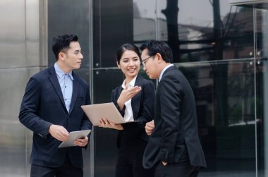 Grup içinde iş insan konuşmaya uygun ve dizüstü bilgisayar birlikte ayakta modern şehir, finans haberleri hakkında bilgi okuma teknolojisi, Internet, başarılı, ekip çalışması kavramı ağ