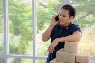 Başlamak yukarıya. genç adam yeni cep telefonu ve teslim parsel kutusunda tablo, evde çalışma office, KOBİ, küçük işletme sahibi ile müşteri online kavramı alışveriş siparişinden sonra mutlu