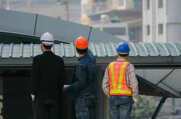 在现代城市建筑背景 施工现场 工人概念等方面 工程师组 商业人员 建筑师与安全头盔的后视图 — 图库照片