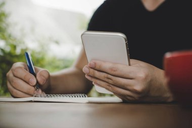 Adam rahat yazma ve dijital cep telefonu ile çalışma, kafeterya restoranında kırmızı kahve fincanı ile belge raporlama, evden çalışma, dijital teknoloji, internet, internet iş konsepti