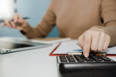 İş kadını hesap makinesinde dizüstü bilgisayar ve belge raporlarıyla finansman üzerinde çalışıyor, ev işi, dijital pazarlama, teknoloji, muhasebeci, iş dünyası finans kavramı