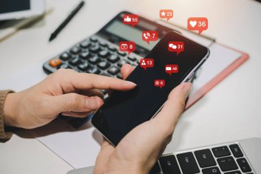 Sanal simge, hesap makinesi ve raporla birlikte dijital cep telefonunda sosyal ağı kullanan kadın eli ev ofisinin masasında, dijital pazarlama, evden çalışma, iş finansmanı, ağ teknolojisi kavramı