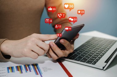 Sanal simge, dizüstü bilgisayar ve raporla birlikte dijital cep telefonunda sosyal ağı kullanarak ev ofisinin masasında, dijital pazarlama, ev işi, iş finansmanı, ağ teknolojisi kavramı