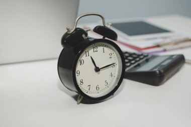 Sayısal dizüstü bilgisayarı, hesap makinesi, dijital mobil tablet ve belge raporlu retro tarzı siyah alarm saati ev ofisindeki beyaz masada gece geç saatlere kadar çalışma, iş finans, nesne kavramı