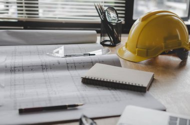 İnşaat aracı, taslak ve sarı güvenlik mimar çalışma masası üzerinde inşaat alanı, inşaat, mühendislik araçları ve mimari konsept toplantı odası ofis merkezinde