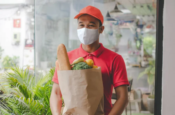 Food Delivery Service Man Protection Face Mask Red Uniform Holding — Stock Photo, Image