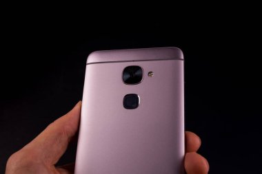 Akıllı telefondan bir el geldi, siyah arkaplan. Akıllı telefon kameraya döndü