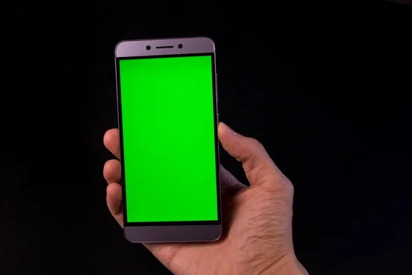 Elinde yeşil ekran, siyah arkaplan olan akıllı telefon.