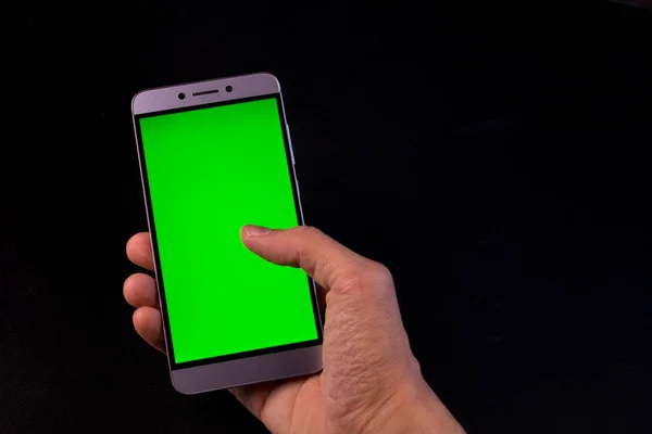 Elinde yeşil ekran, siyah arkaplan olan akıllı telefon.