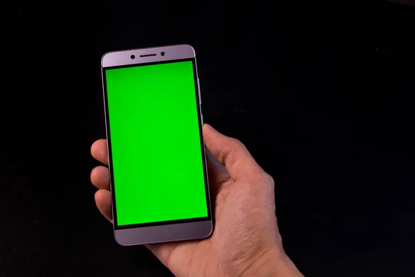 Elinde yeşil ekran, siyah arkaplan olan akıllı telefon.