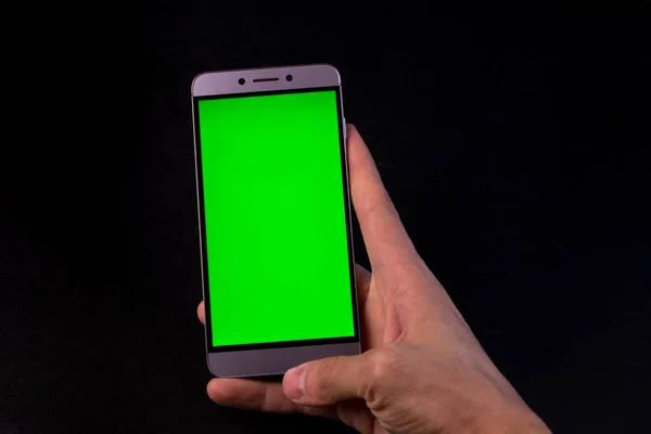 smartphone with a green screen in hand, black background