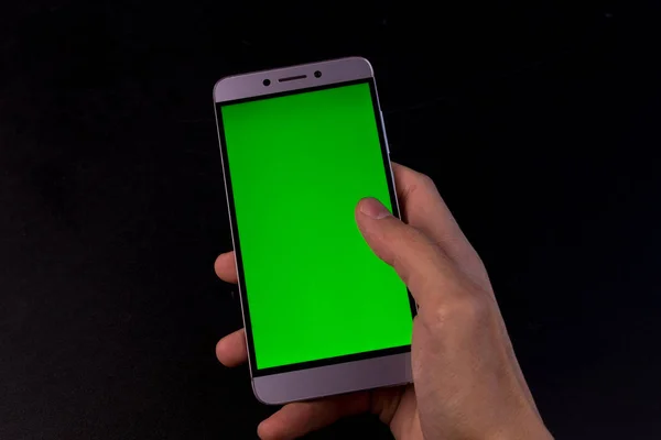 Elinde yeşil ekran, siyah arkaplan olan akıllı telefon.