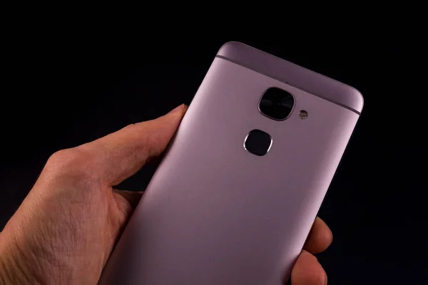 Akıllı telefondan bir el geldi, siyah arkaplan. Akıllı telefon kameraya döndü