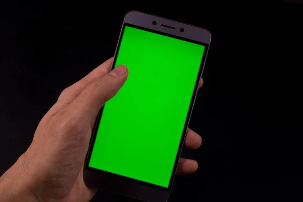 Elinde yeşil ekran, siyah arkaplan olan akıllı telefon.