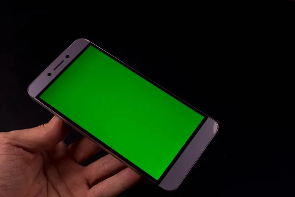 Elinde yeşil ekran, siyah arkaplan olan akıllı telefon.