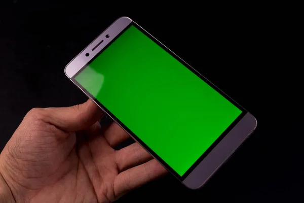 Elinde yeşil ekran, siyah arkaplan olan akıllı telefon.