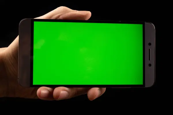 Elinde yeşil ekran, siyah arkaplan olan akıllı telefon.