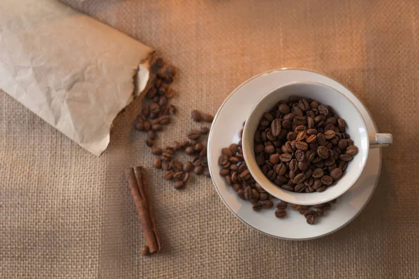 Doğal ambalajdan gelen kahve çekirdekleri yüz taneye dağılmış. Kahve kupası.