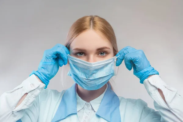 girl doctor puts on a mask on a white background, suitable for work on the topic of infection or virus