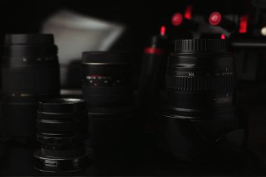 Karanlık arka planda lensler ve diğer ekipmanlar, fotoğrafçıların web sayfası başlığı için uygundur