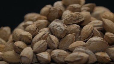 Badem ahşap bir masa üzerine siyah izole kabuk içinde yığını