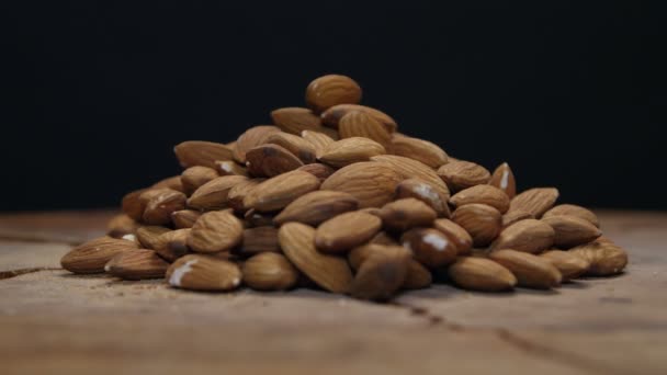 Stapel van amandelen op een houten tafel geïsoleerd op zwart — Stockvideo