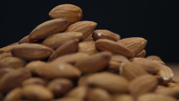 Pile of almonds on a wooden table isolated on black — Stock Video