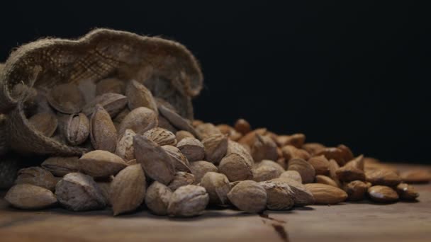 Deux piles d'amandes en coquille et décortiquées sur une table en bois isolée sur du noir — Video