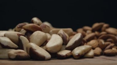 Ahşap bir masa üzerine siyah izole karışık Kuruyemiş yığınları
