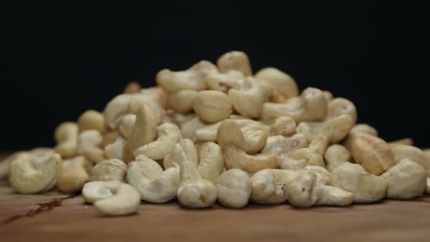 Hromadu Kešu ořechy na dřevěný stůl izolované na černém pozadí — Stock video
